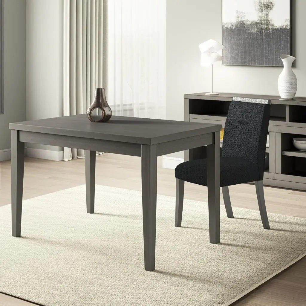 Gray wooden dining table with tapered legs and black upholstered chair, set in a modern living room.