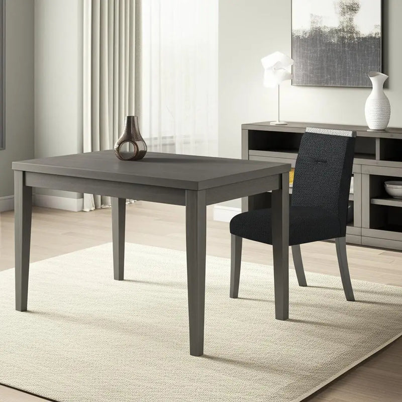 Gray wooden dining table with tapered legs and black upholstered chair, set in a modern living room.