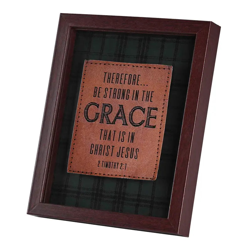 Framed brown leather quote plaque with black and green plaid background, featuring an inspirational message.