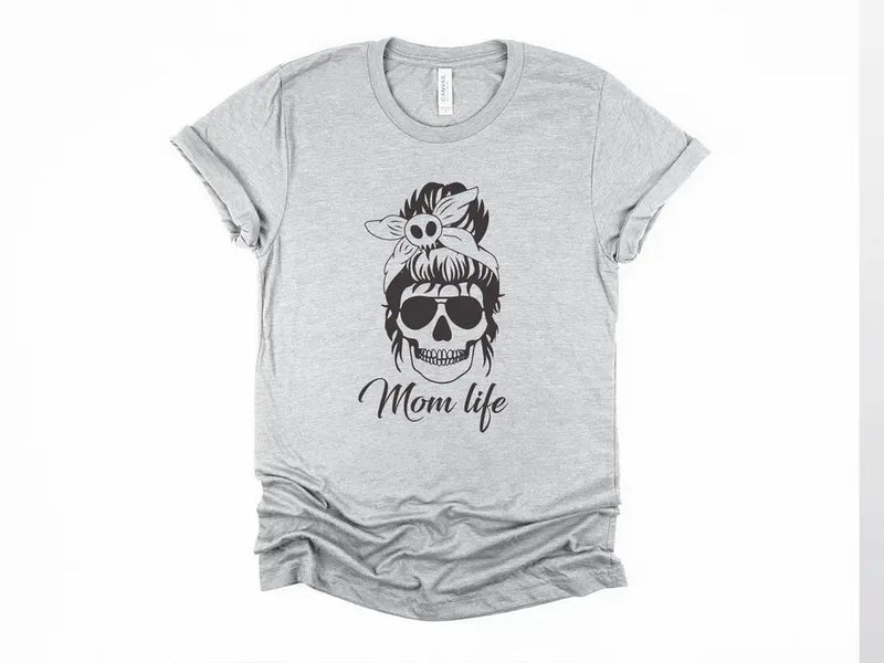 Gray t-shirt featuring a stylish skull design with a bow and "Mom life" text in black. Casual, trendy women's wear.