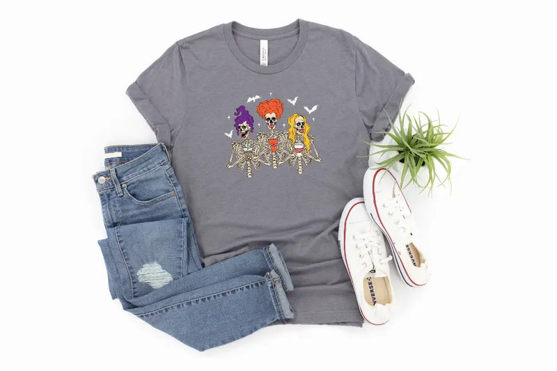 Gray skeleton graphic tee featuring colorful wigs, paired with distressed denim jeans and white sneakers.
