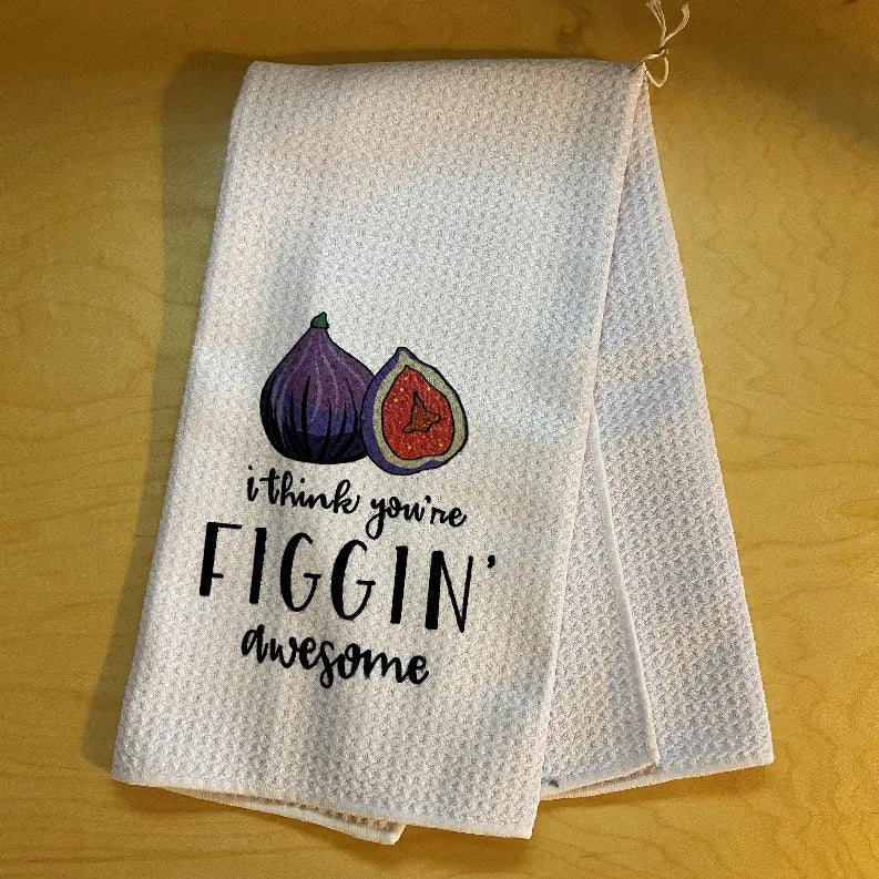 White textured kitchen towel featuring colorful fig illustrations and "I think you're figgin' awesome" text.