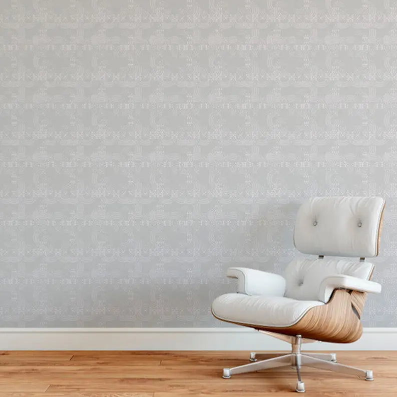 Light gray patterned wallpaper with a modern white leather chair featuring a wooden base on a warm wooden floor.