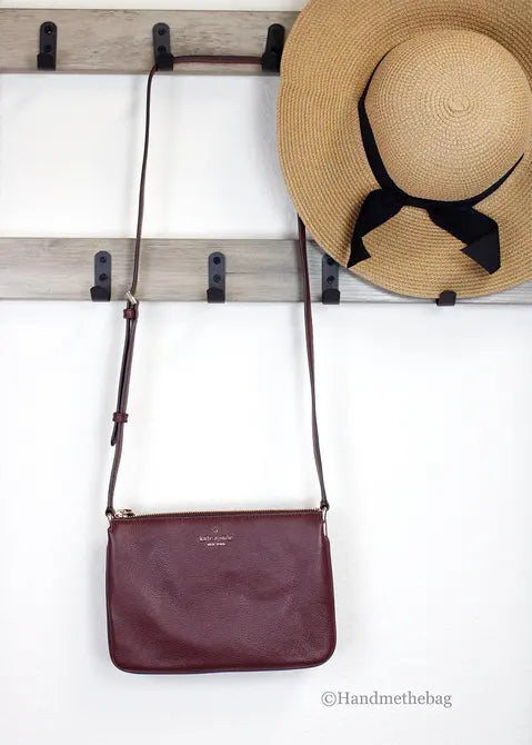 Brown leather crossbody bag with adjustable strap, paired with a straw hat and black bow, stylish and versatile accessory.