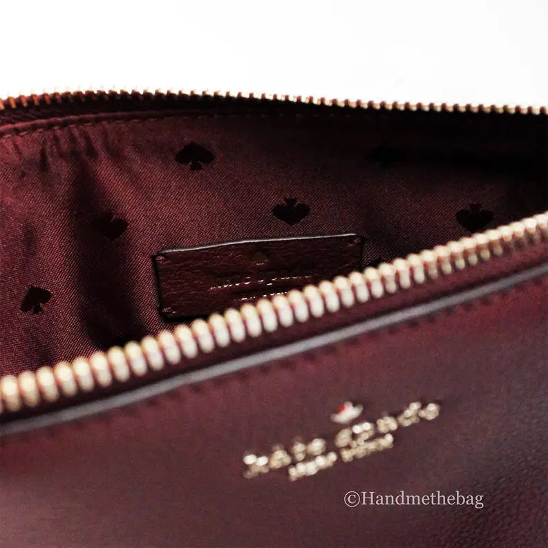 Interior view of a burgundy Kate Spade bag with gold accents and heart-patterned lining.