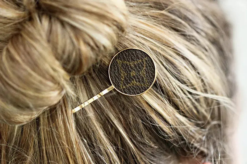Gold hairpin with a brown patterned round top, perfect for elegant updos and stylish hair accessories.