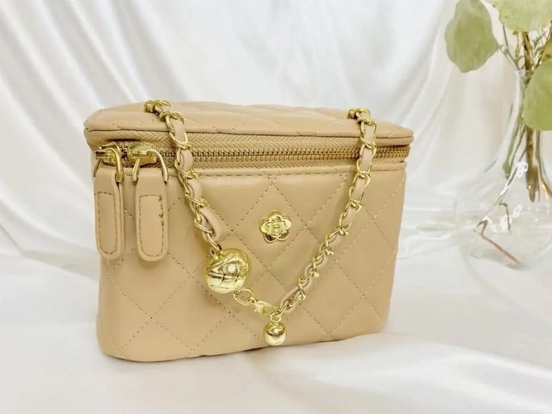 Beige quilted cosmetic bag with gold chain and charm, perfect for stylish organization.