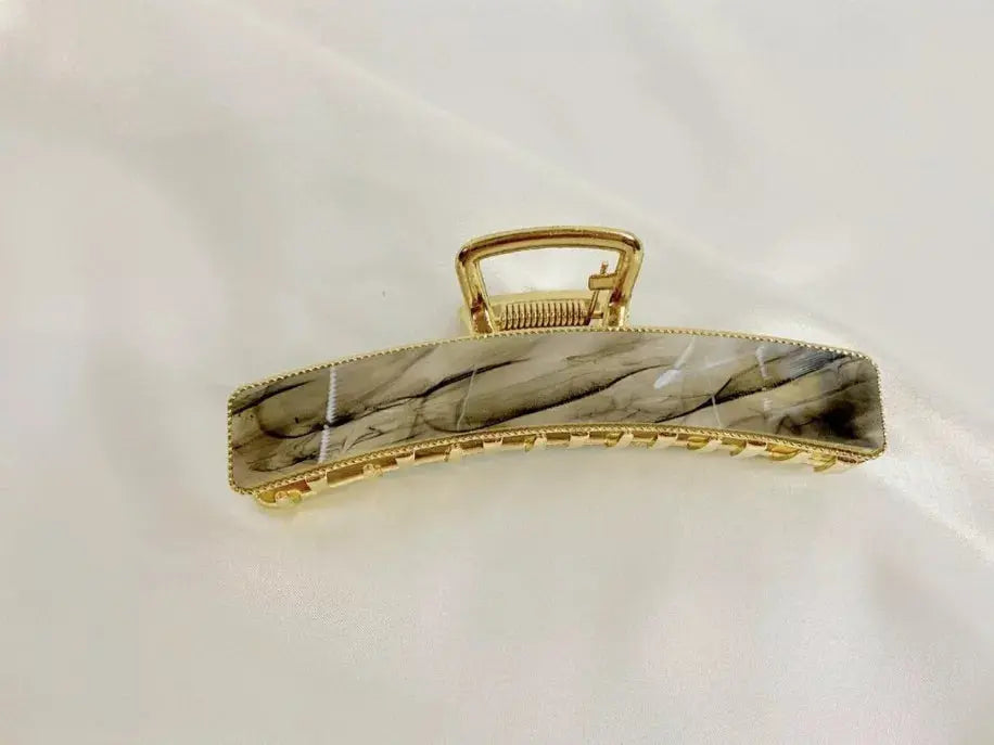 Marble effect hair claw clip in beige and black with gold accents, perfect for elegant updos.