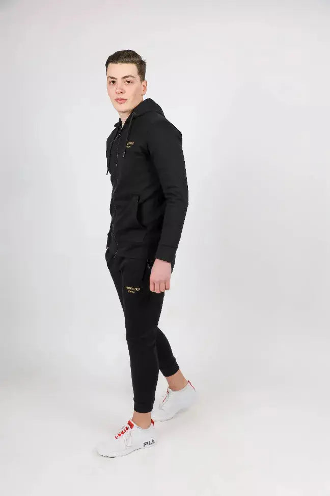 Men's black hoodie and jogger set with gold accents, paired with white and red athletic shoes. Stylish and comfortable outfit.