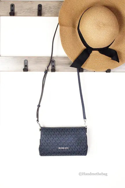 Black patterned crossbody bag with adjustable strap, paired with a straw hat featuring a black bow.