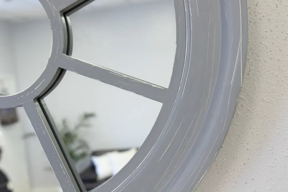 Round gray wooden wall mirror with a unique paneled design, adding modern elegance to any space.