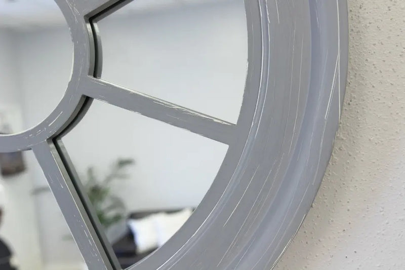 Round gray wooden wall mirror with a unique paneled design, adding modern elegance to any space.