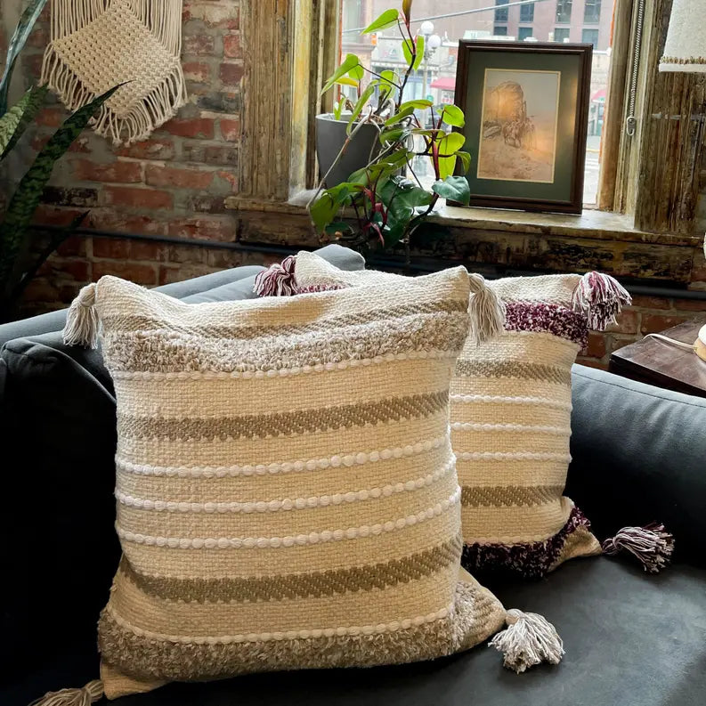 Boho-style cream and beige throw pillows with tassels, featuring textured stripes, perfect for cozy decor.
