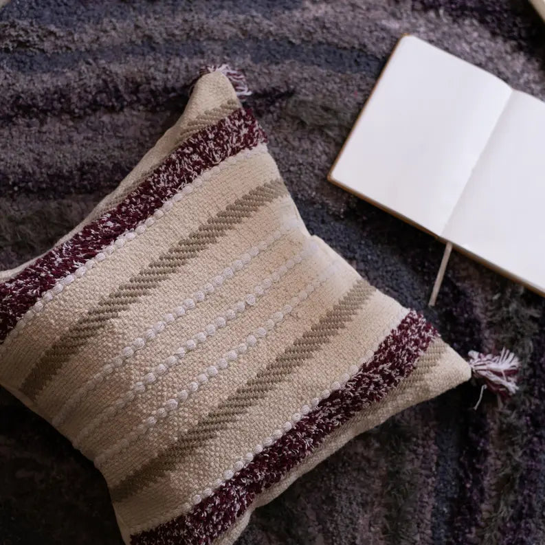 Textured beige and burgundy striped decorative pillow with tassels, perfect for a cozy home decor accent.