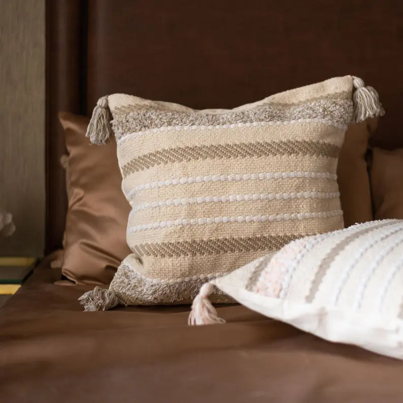 Beige and taupe striped decorative pillow with tassels, woven texture, perfect for cozy bedroom décor.