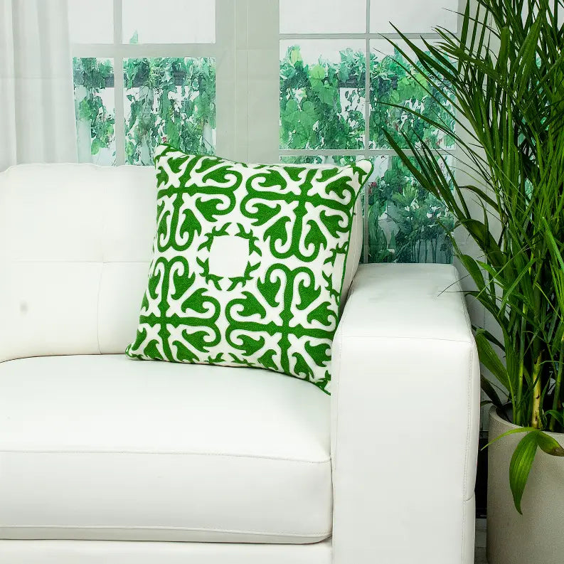Green patterned decorative pillow on a white couch, featuring a stylish geometric design in soft fabric.