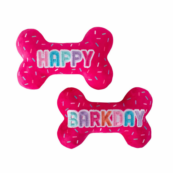 Bright pink plush dog toys in bone shape, featuring "HAPPY" and "BARKDAY" with colorful sprinkles. Perfect for celebrations!