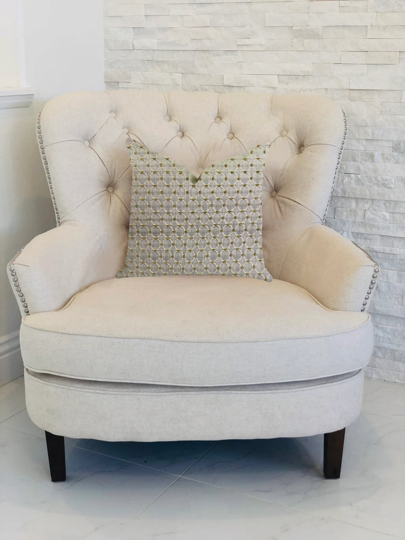 Beige tufted accent chair with decorative gray and gold geometric pillow on dark wooden legs, perfect for modern decor.