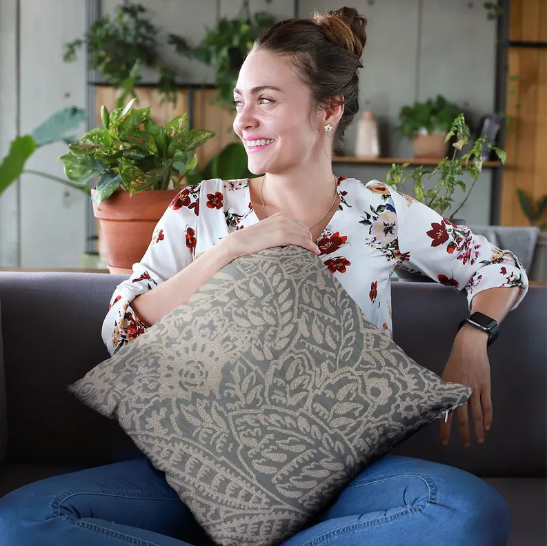 Beige floral patterned throw pillow, soft fabric, ideal for modern home decor, with a woman in a floral blouse.