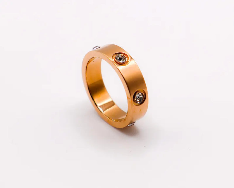Rose gold stainless steel ring with three cubic zirconia accents, modern minimalist style.