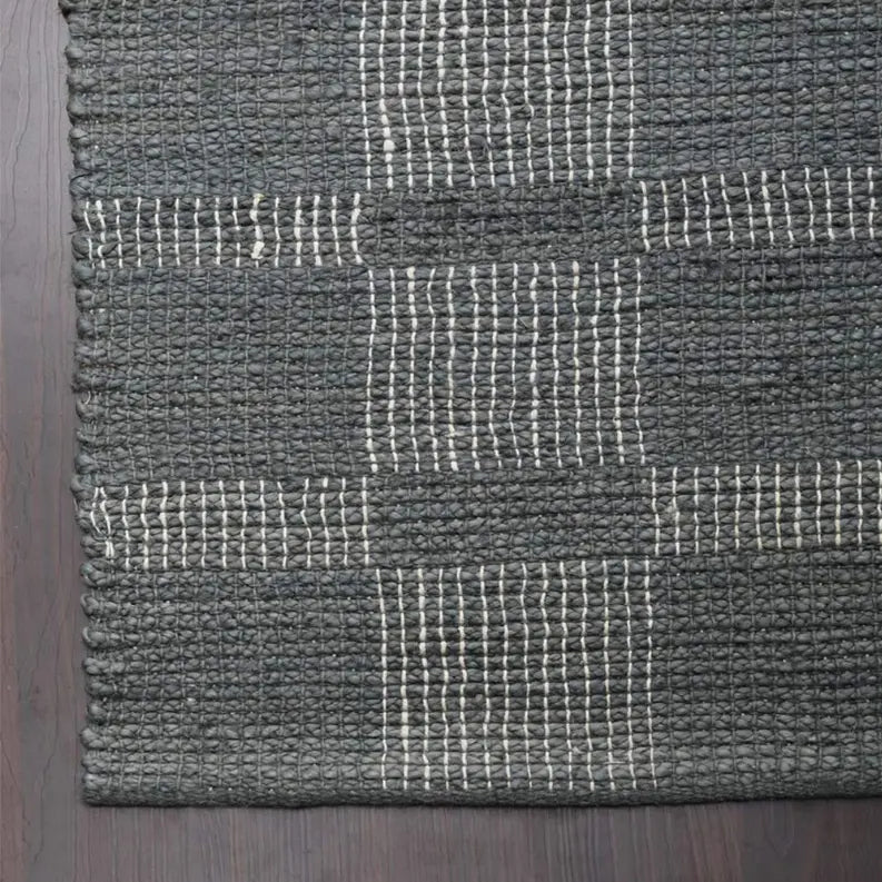 Handwoven black and cream striped jute rug, featuring a textured pattern, perfect for modern and rustic interiors.