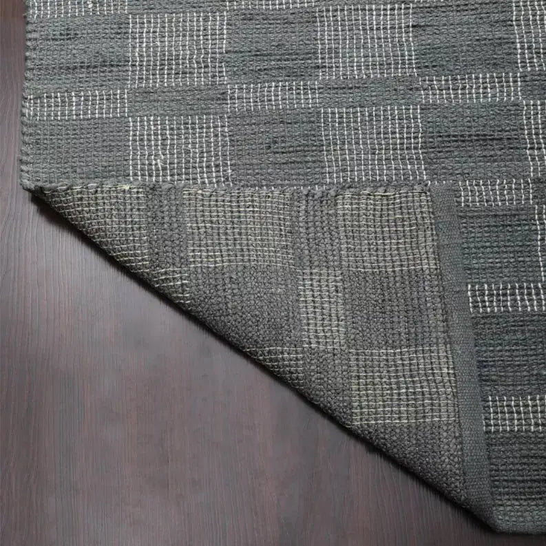 Gray woven rug with a textured checkerboard pattern, ideal for modern decor and indoor spaces.