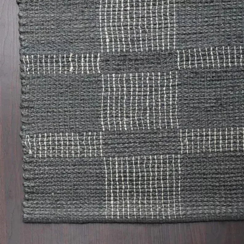 Handwoven black and white jute rug with a textured geometric pattern, ideal for modern decor.