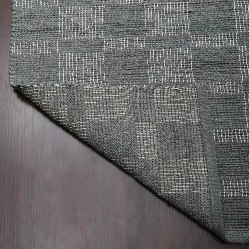 Gray woven area rug with a checkered pattern, featuring textured detailing and a low-profile edge.