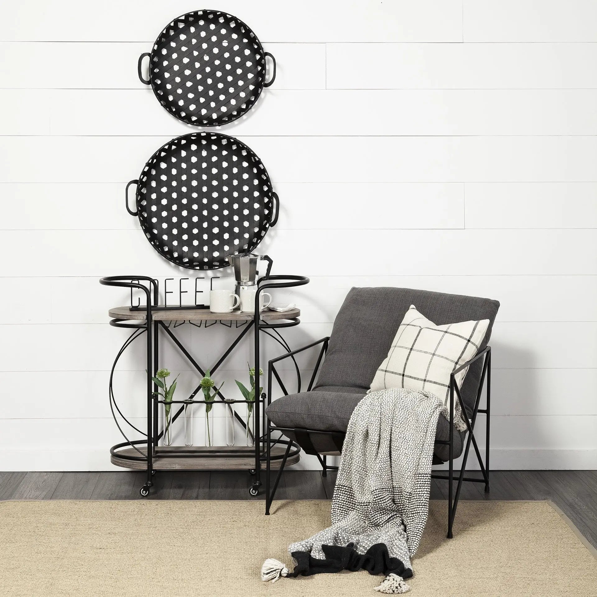 Modern gray fabric accent chair with black metal frame, paired with polka dot trays and a stylish wooden cart.