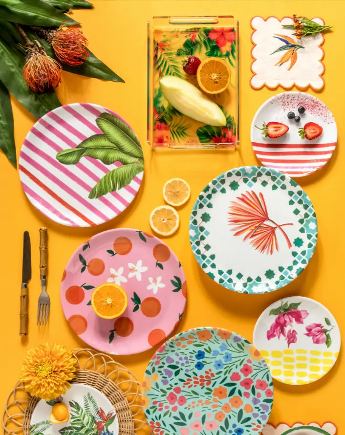 Colorful ceramic dinner plates with floral and tropical designs on a vibrant yellow background. Perfect for summer dining.