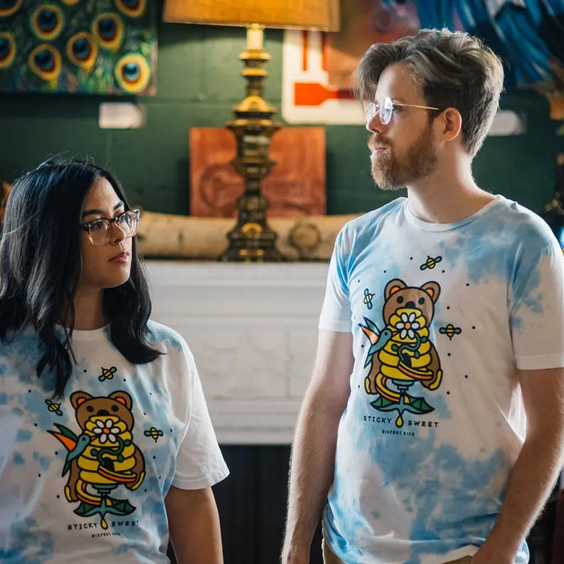 Blue tie-dye t-shirt featuring cartoon bear holding flowers, perfect for casual summer wear. Unisex style for all.
