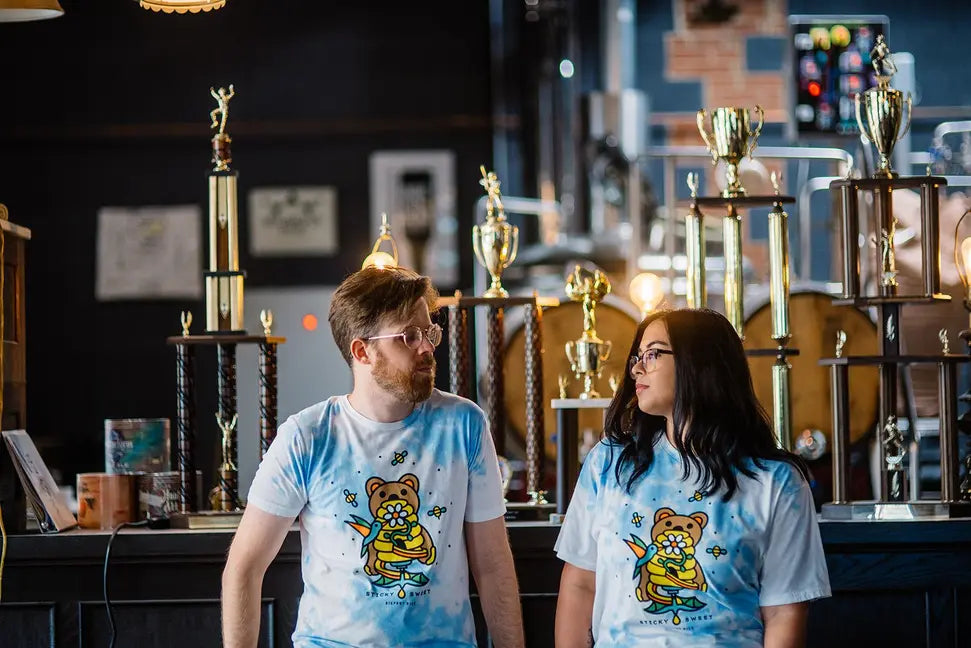 Unisex tie-dye t-shirt in light blue featuring a cartoon bear design, perfect for casual wear or gifts.