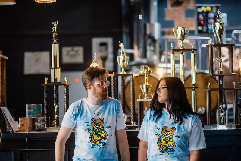 Unisex tie-dye t-shirt in light blue featuring a cartoon bear design, perfect for casual wear or gifts.