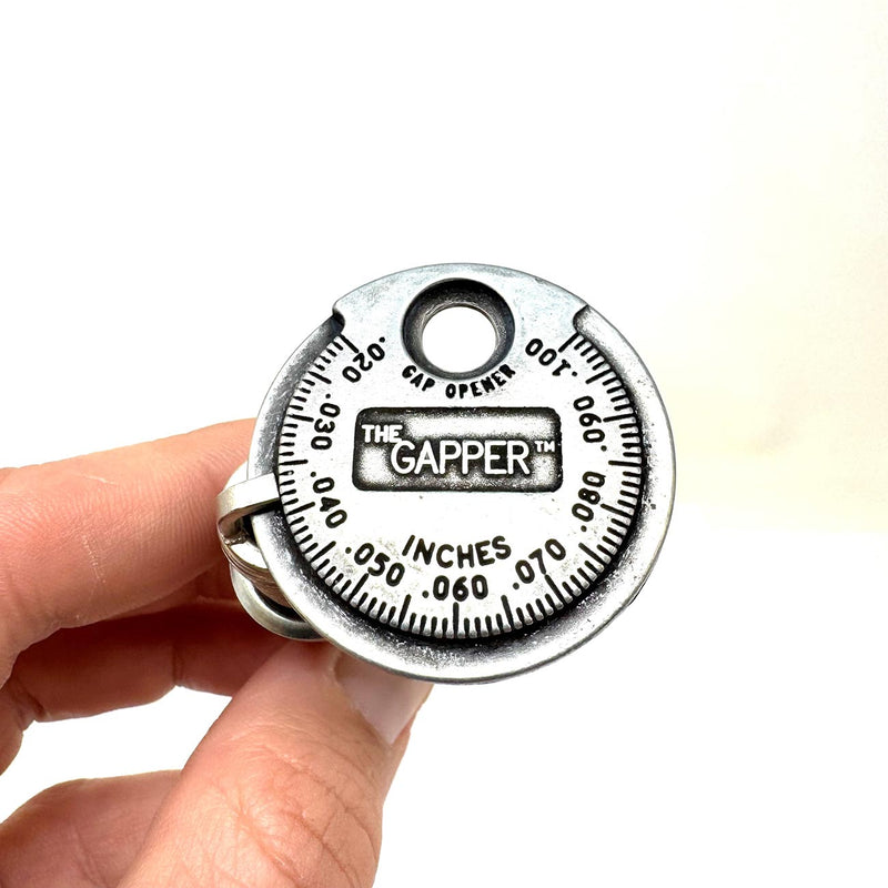 Spark plug gapper tool with inches gap scale held in hand, label The GAPPER visible