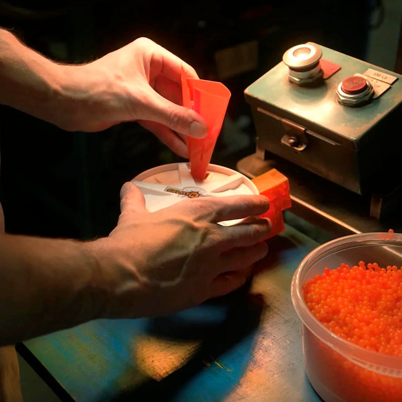 Orange round drum magazine being loaded by hand; 800-round capacity