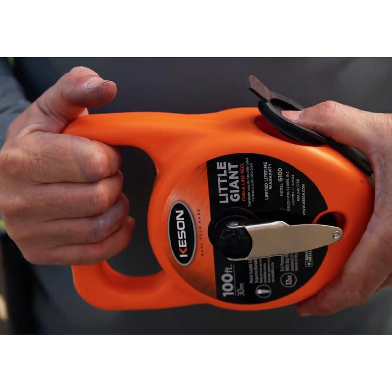 Orange chalk line reel in hand, close-up of line window and metal crank