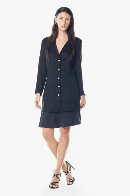 Black long-sleeve blazer dress with gold buttons, layered over a pleated gray skirt, stylish and chic for any occasion.