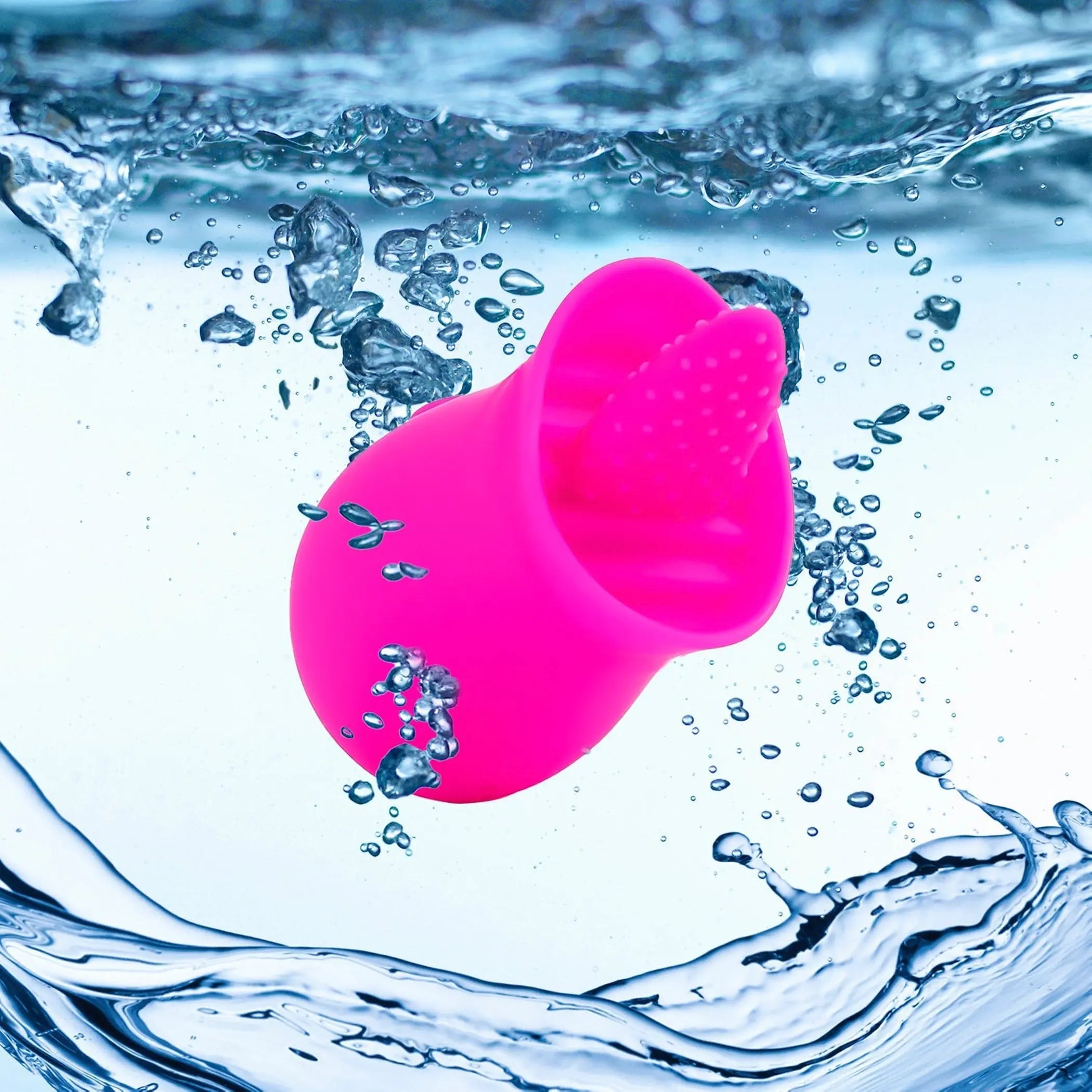 Bright pink silicone facial cleansing brush floating in water, featuring soft rubber bristles for gentle exfoliation.