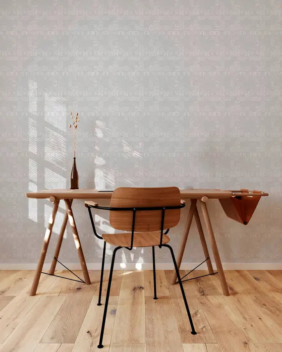 Scandinavian-style wooden desk with black metal chair, featuring a soft gray patterned wallpaper and warm wooden floor.