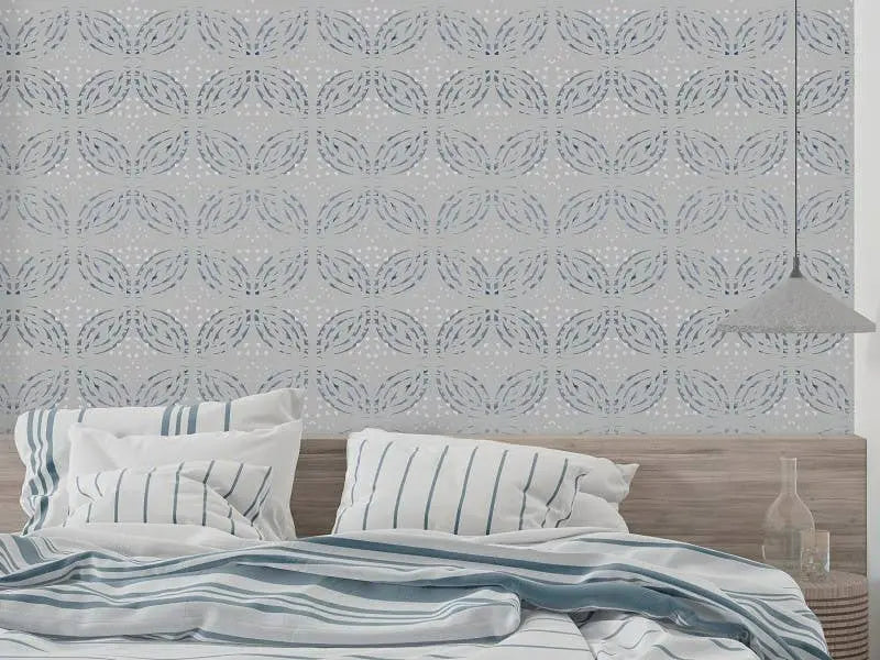 Light blue patterned wallpaper featuring delicate leaf motifs, complementing a cozy bed with striped sheets and pillows.