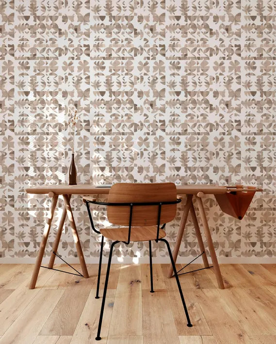 Modern wooden desk with a black chair, set against a beige patterned wallpaper and warm wood flooring.