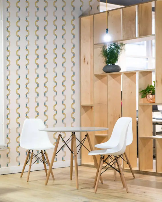Modern white dining chairs with wooden legs at a round table, set against a chic patterned wallpaper backdrop.