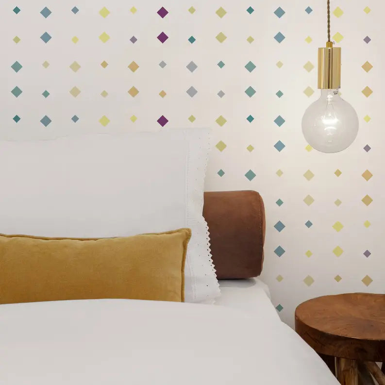 Cozy bedroom featuring white bedding, mustard yellow throw pillow, wooden bedside table, and colorful diamond-patterned wallpaper.