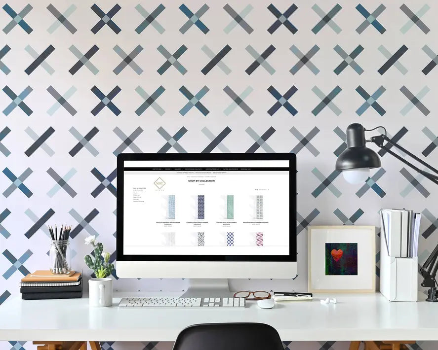 Modern workspace with a computer on a white desk, featuring a blue and gray patterned wallpaper.