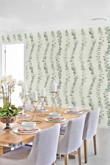 Eucalyptus-patterned wallpaper in soft green and cream, enhancing a modern dining room with stylish decor.