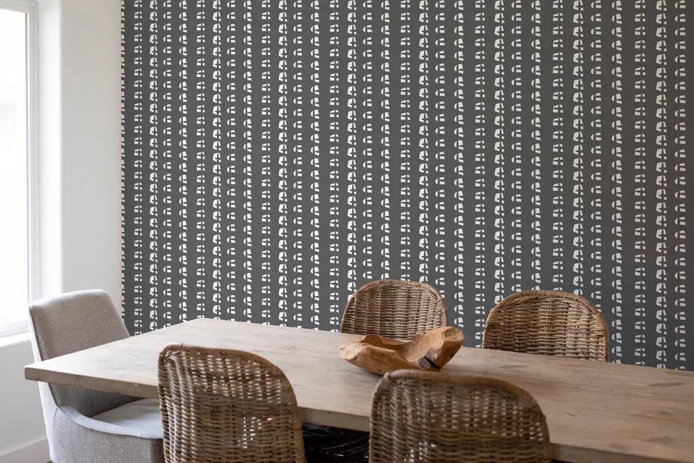 Gray patterned wallpaper with white geometric designs, perfect for modern dining spaces. Features natural wood table and woven chairs.