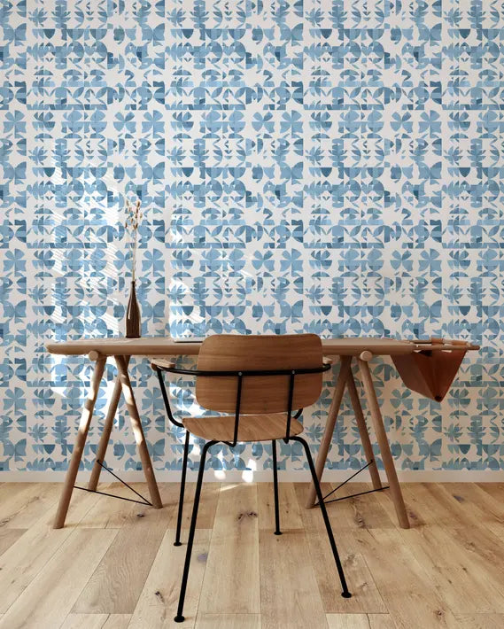 Blue and white botanical wallpaper in a modern dining room with a wooden table and black chair on light hardwood floor.