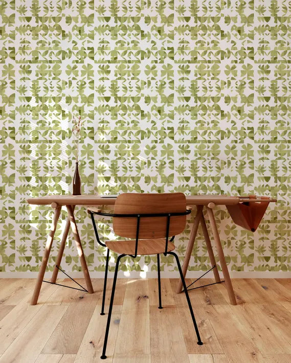 Green botanical patterned wallpaper in a modern workspace with a wooden desk and black wire chair.
