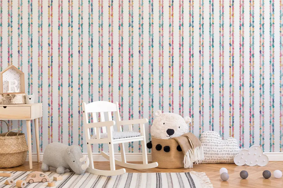 White wooden rocking chair against pastel floral striped wallpaper, featuring soft toys and woven baskets in a cozy nursery setting.