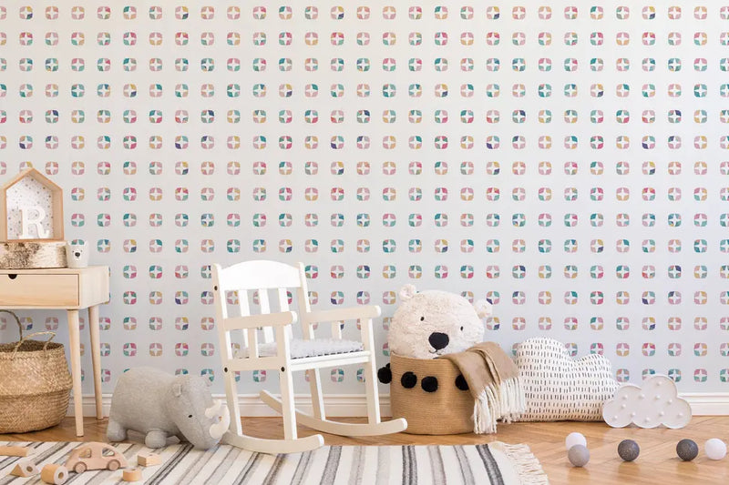 Pastel patterned wallpaper in soft colors, with a white wooden rocking chair and cozy plush toys in a stylish nursery setting.